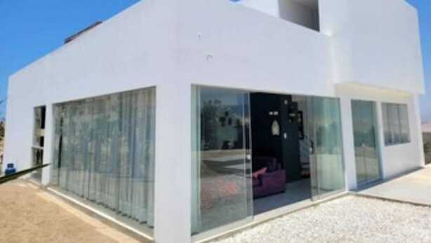 Un edificio moderno de color blanco con amplios ventanales y un espacio interior visible.