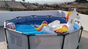Una piscina inflable con diseño de unicornio y flamenco, rodeada por una estructura de piscina blanca con detalles negros.