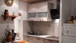 Une cuisine compacte dotée d’un îlot central, d’un plafond en bois et de meubles blancs.