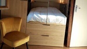 Une chambre avec un lit superposé, un lit simple, une chaise et une armoire.