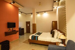 A modern hotel room with a large bed, a television, a desk, and a wardrobe. - Aristro Club (Alipur)