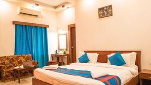 A hotel room with a large bed, a sofa, a desk, and an air conditioning unit. - Aristro Club (Alipur)