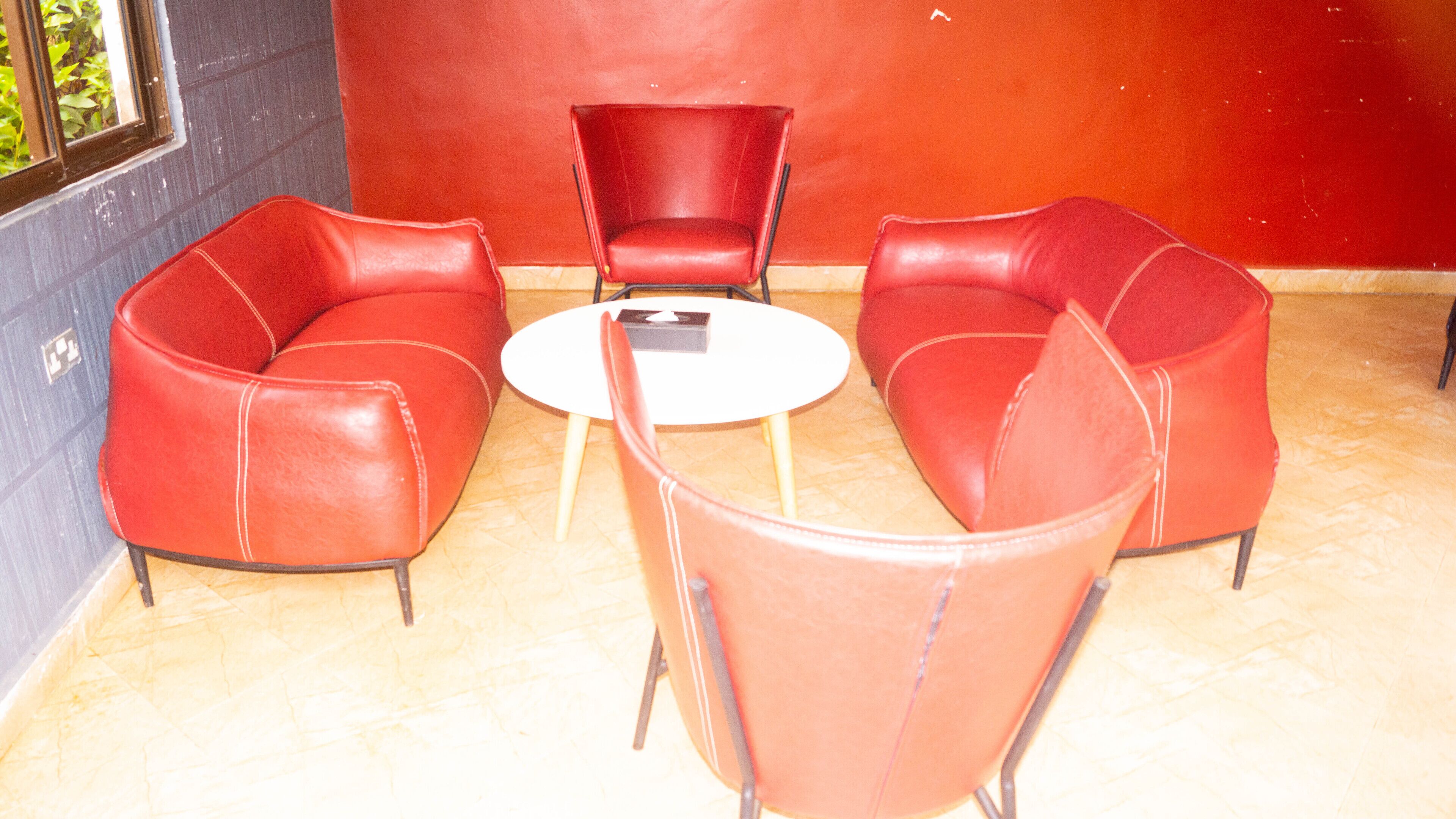 Un coin salon avec deux canapés en cuir rouge et une petite table blanche.