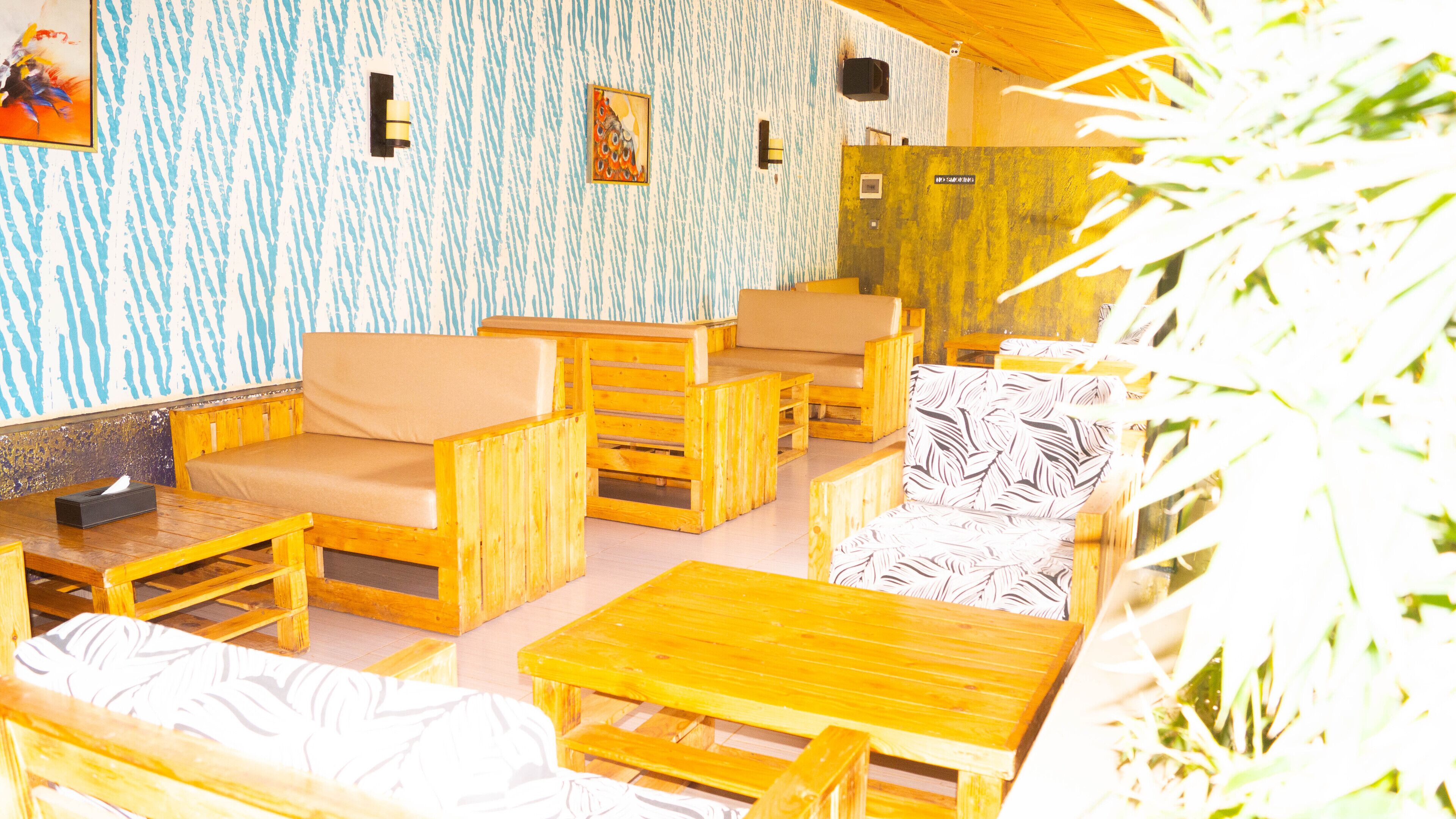 A wooden interior with seating and tables, a patterned wall, and a door.