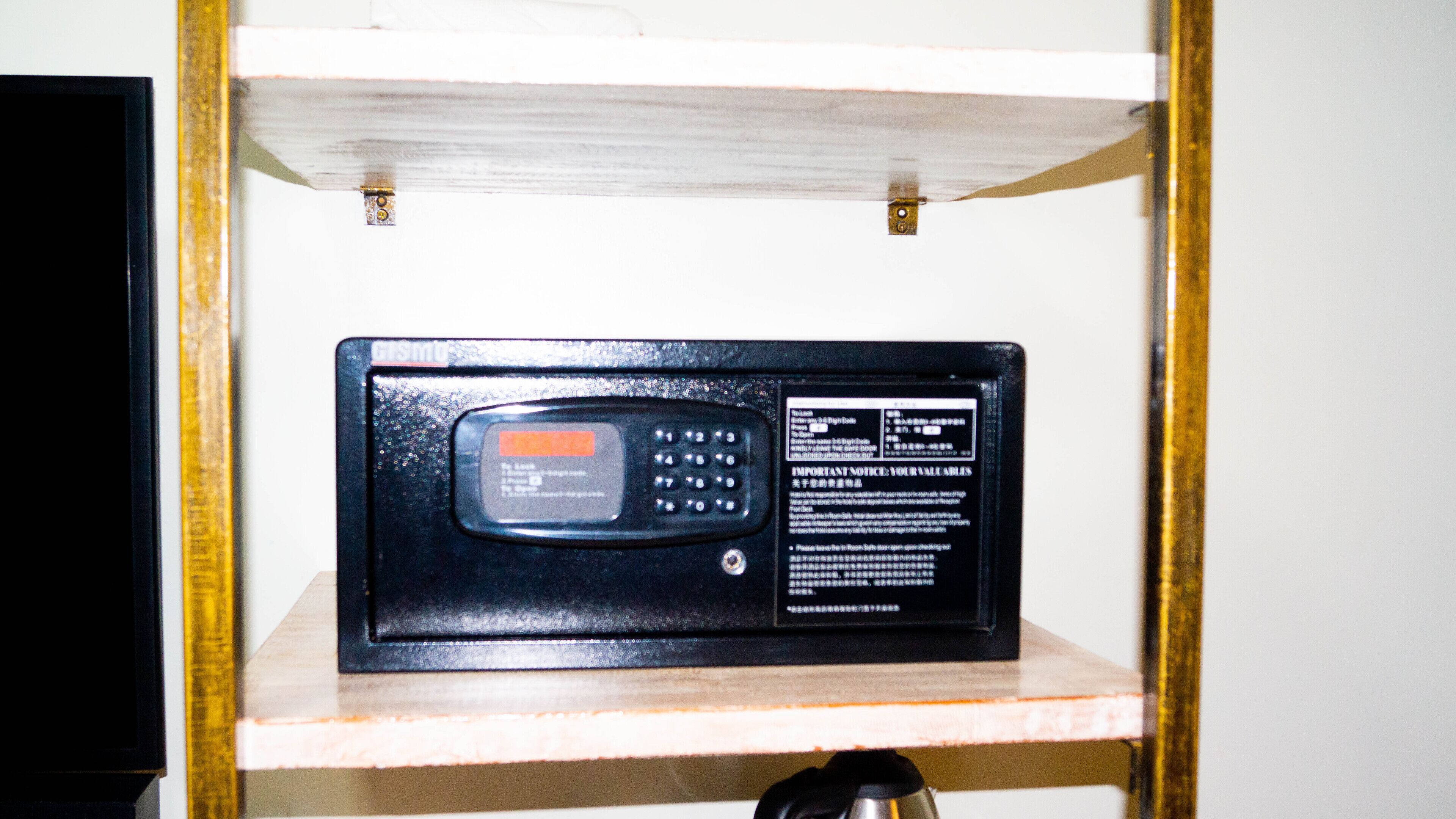 A black electronic device with a keypad and a screen, mounted on a wooden shelf.