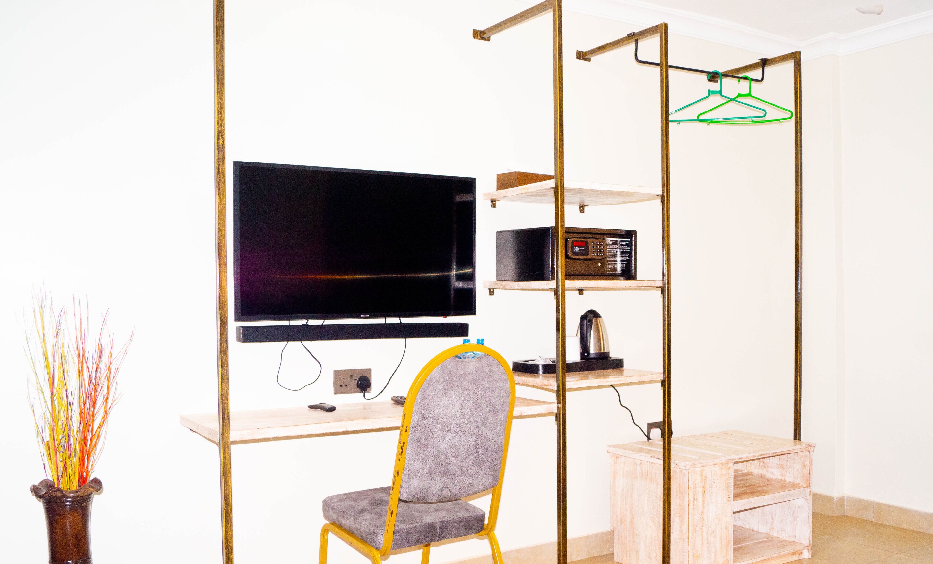 Un espacio habitable compacto con televisión de pantalla plana, una kitchenette pequeña y una silla.