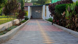 A paved pathway leading to a building with a signboard. - Distinction Gardens (Siaya)