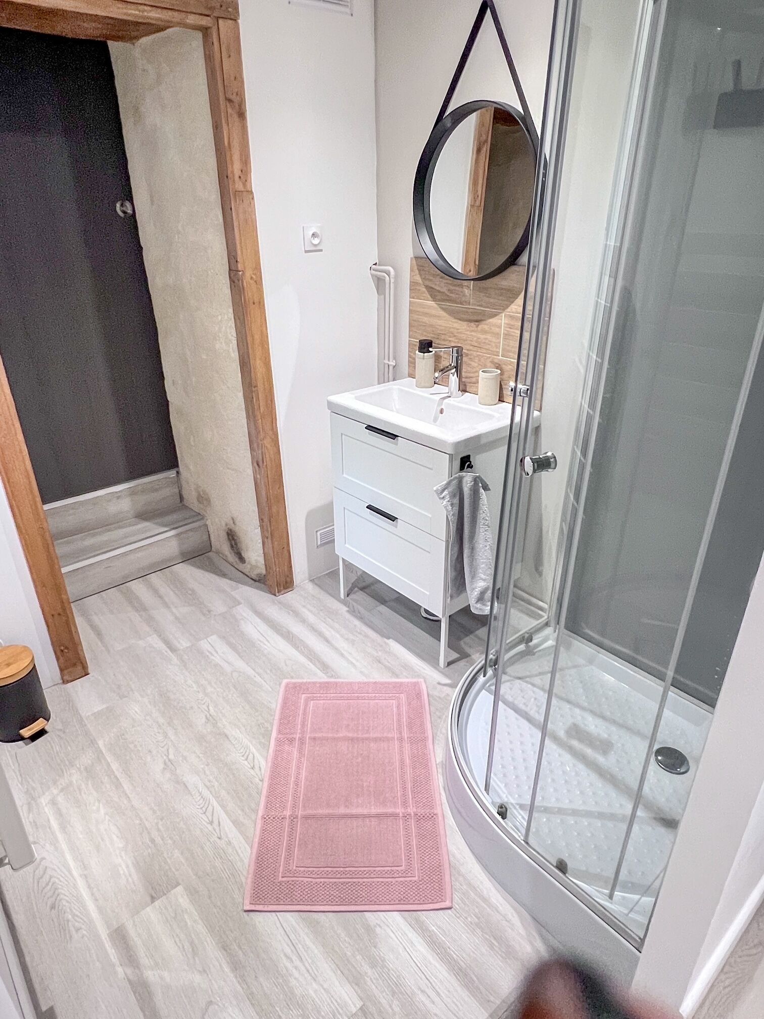 Un baño con lavamanos blanco, espejo y cabina de ducha de vidrio.