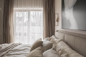 A bedroom with a large bed, sheer curtains, a framed artwork, and a view through the window. - Apartment with church view in Vilnius Old Town (Vilnius)