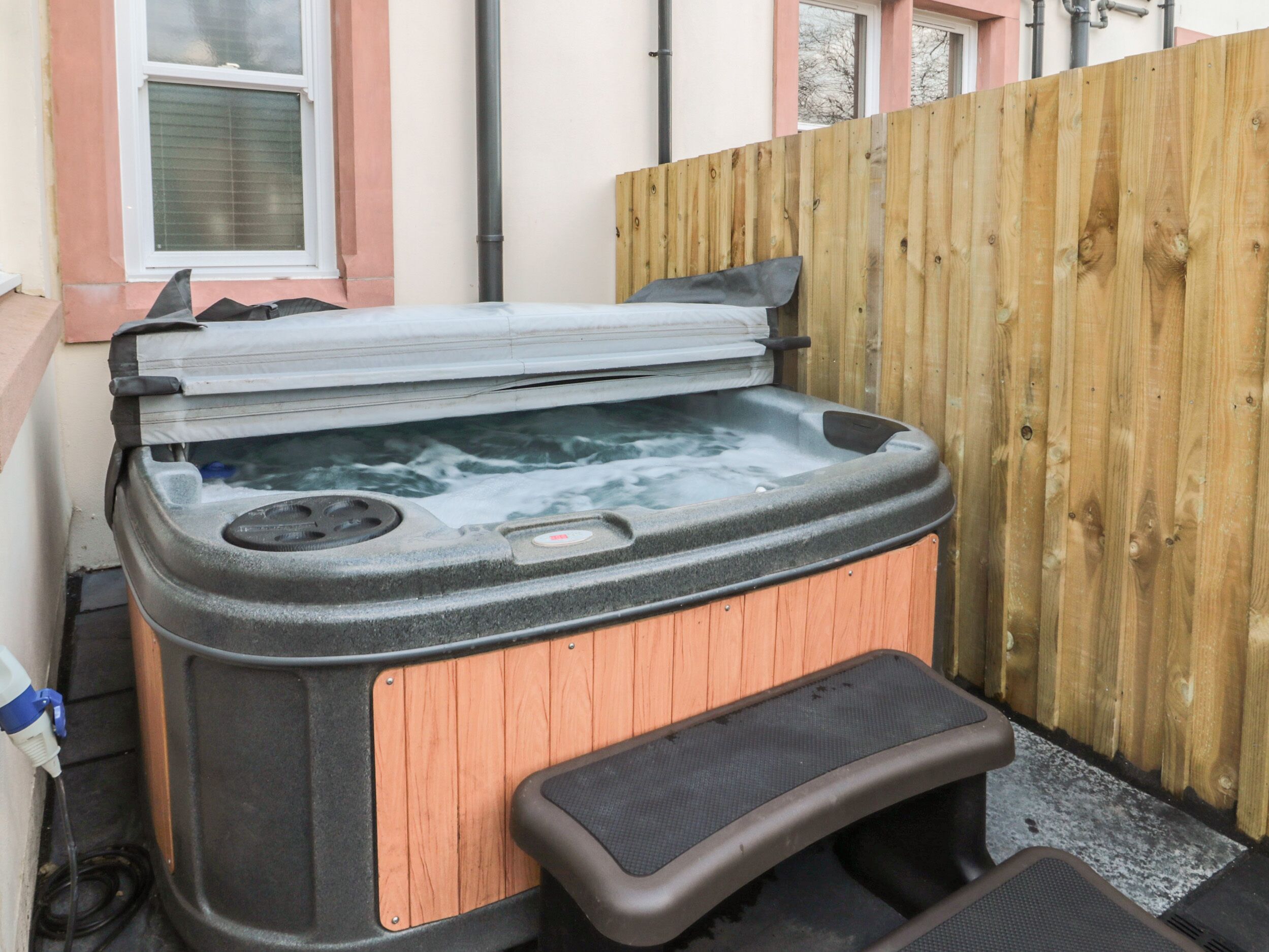 Un jacuzzi con revestimiento de madera y un escalón para facilitar el acceso.