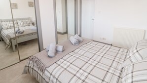 Une chambre à coucher avec un lit, un miroir, un radiateur et une porte.