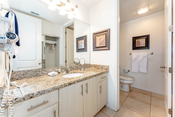 A bathroom with a granite countertop, a white sink, a mirror, and framed pictures on the wall.