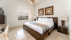 Un dormitorio con cama, mesitas de noche, escritorio y ventana.