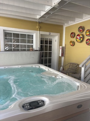 A hot tub with a control panel, a door with the number 3, and fruit-themed wall decorations.