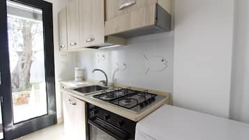 Een koelkast, een oven, een kookplaat, kookgerei, borden en bestek