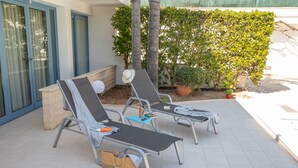 Eine Terrasse mit zwei Liegestühlen, einem kleinen Tisch und einem Korb.