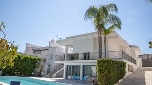 Ein modernes, zweistöckiges Haus mit Swimmingpool, Balkon und einer Treppe, die zum Obergeschoss führt.