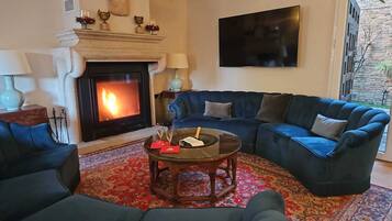A living room with a fireplace, a blue sofa set, a coffee table, and a TV mounted on the wall.