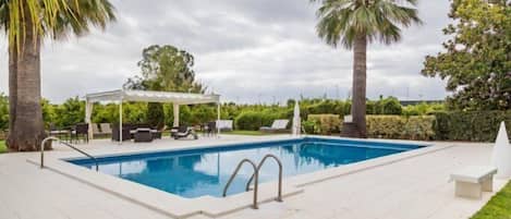 Una piscina al aire libre, sombrillas, tumbonas