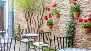Een terras met stenen muren, plantenpotten en tuinmeubilair.