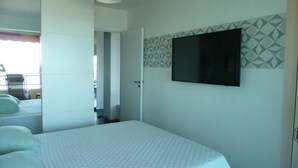 Ein Hotelzimmer mit einem Bett, einem an der Wand befestigten Fernseher und einer Tür zu einem anderen Raum.