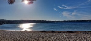 A beach with a clear sky, calm water, and distant hills. - Le Palm Beach - Panoramic view of Bandol Bay - Everything within walking distance (Bandol)