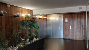 Ein moderner Aufzugsbereich mit Holzvertäfelung und einer Pflanzengestaltung.