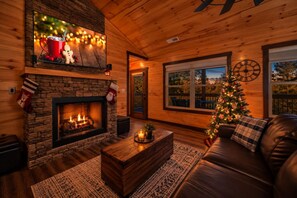 A cozy living room with a fireplace, a Christmas tree, and a leather sofa.