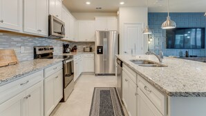 A modern kitchen with white cabinets, stainless steel appliances, and a granite countertop.