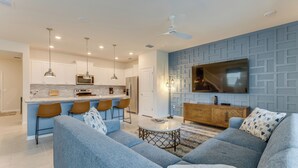 A modern living room with a blue sofa, a coffee table, and a TV mounted on the wall.