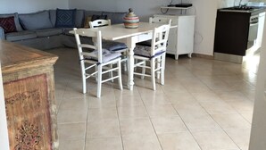 A dining area with a table and chairs, a sofa, a television, and a kitchen area with a sink and stove.