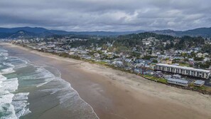 A coastal town with a beach, houses, and a large building with a flat roof.