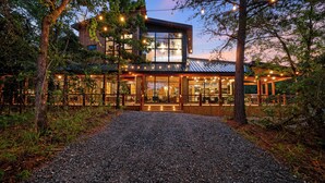 Uma casa moderna com grandes janelas e uma entrada com calçamento de brita.