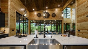Uma cozinha moderna com uma ilha grande, eletrodomésticos de aço inoxidável e amplas janelas com vista para o exterior.