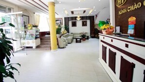 Un hall d’hôtel comprenant un comptoir d’accueil, un espace salon et un escalier menant à un autre étage.