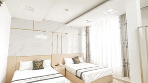 Une chambre d’hôtel moderne avec deux lits, un ventilateur de plafond et une grande fenêtre avec des rideaux.