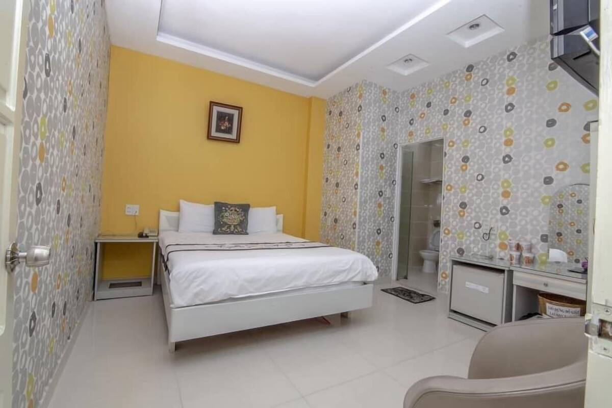 A bedroom with a bed, bedside table, and a small desk with a chair.
