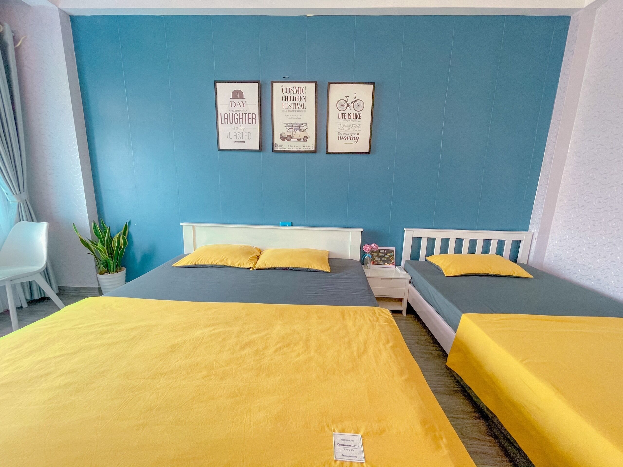 A hotel room with two beds, a nightstand, a chair, and a potted plant.