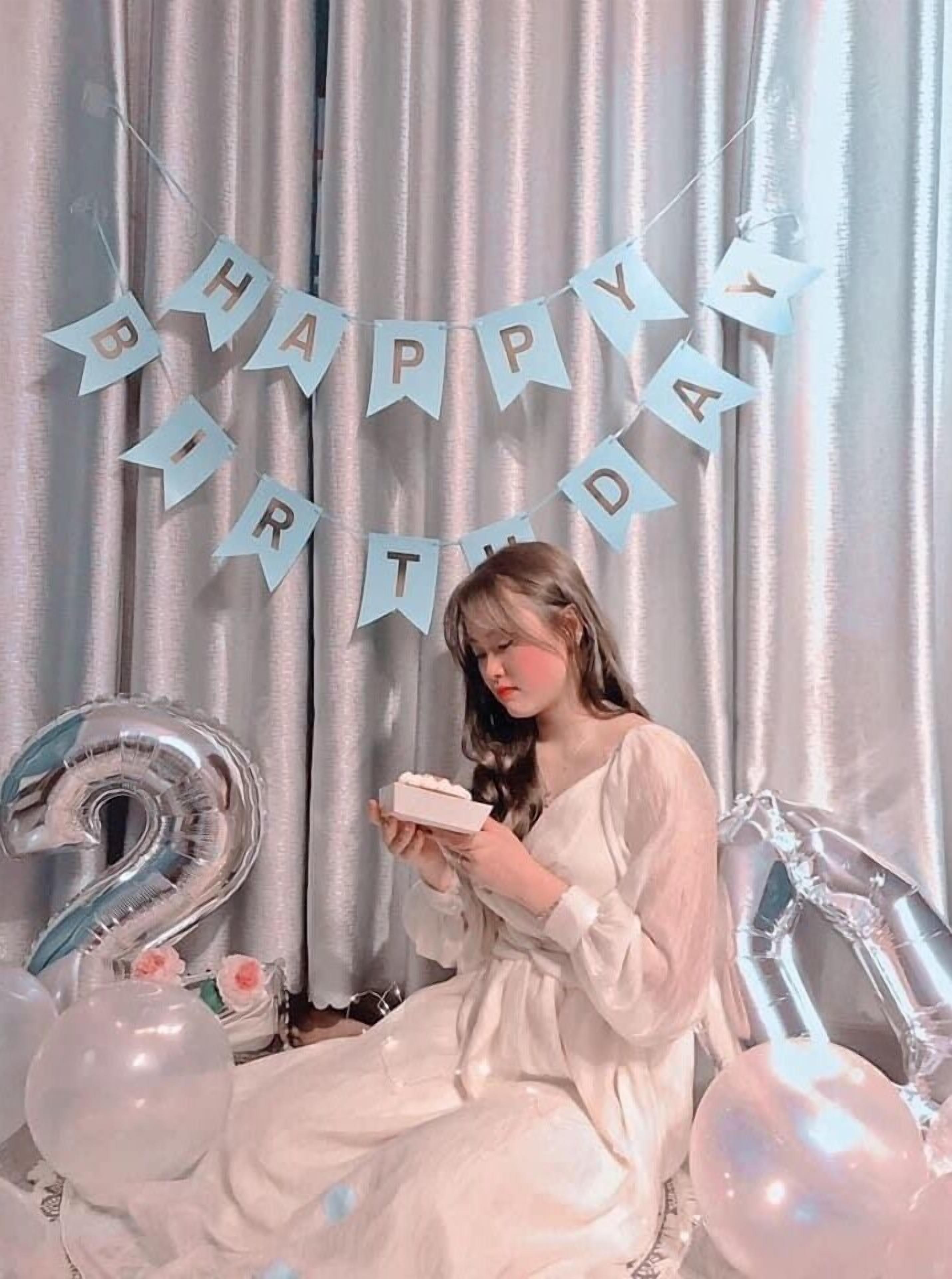 Una persona sentada en una silla con un cartel de 'Happy Birthday' al fondo.