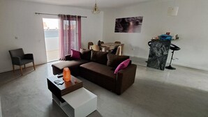 Een moderne woonkamer met een bank, salontafel en een eethoek met tafel en stoelen.
