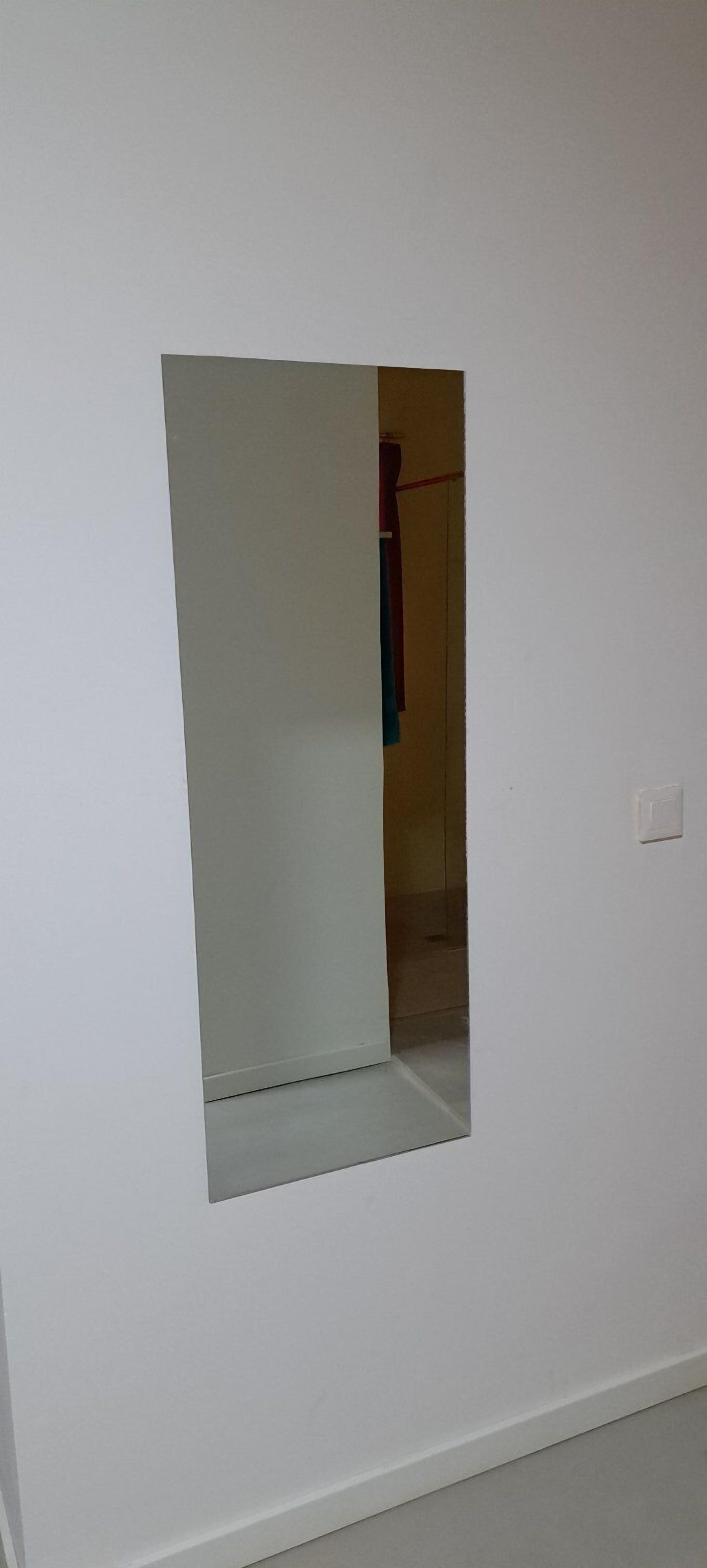 A room with a white wall and a small window.