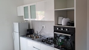 Een keuken met witte kasten, een dubbele spoelbak, een kookplaat en een koffiezetapparaat.