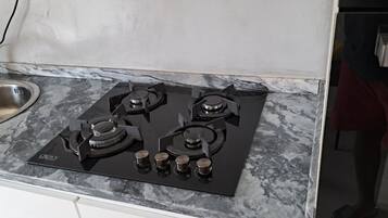 Una cocina con estufa a gas de cuatro quemadores, un lavamanos de acero inoxidable y encimera de mármol.