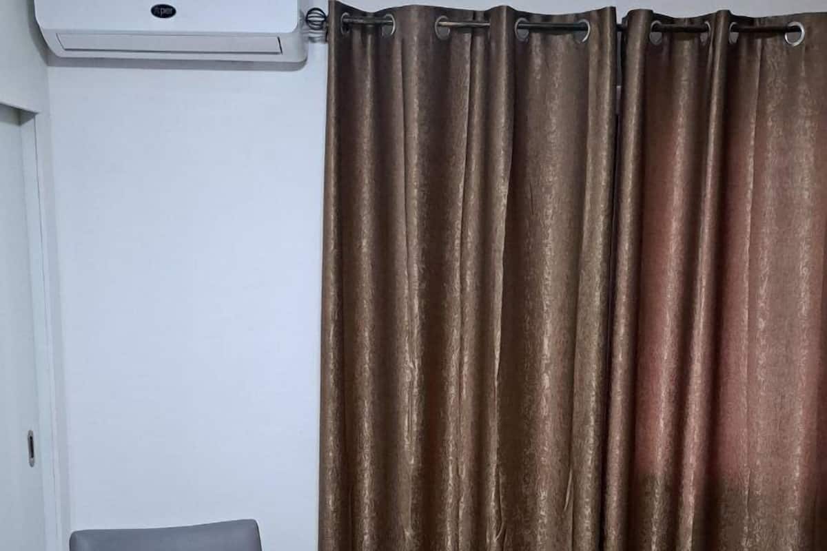 Une chambre avec un lit, une chaise et un appareil de climatisation.