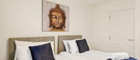 A hotel room with a bed, a wall-mounted Buddha statue, and a door.