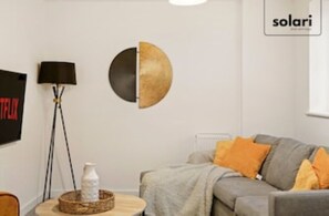 Relax in this stylish living room with a grey sofa, round coffee table, and flat-screen TV.