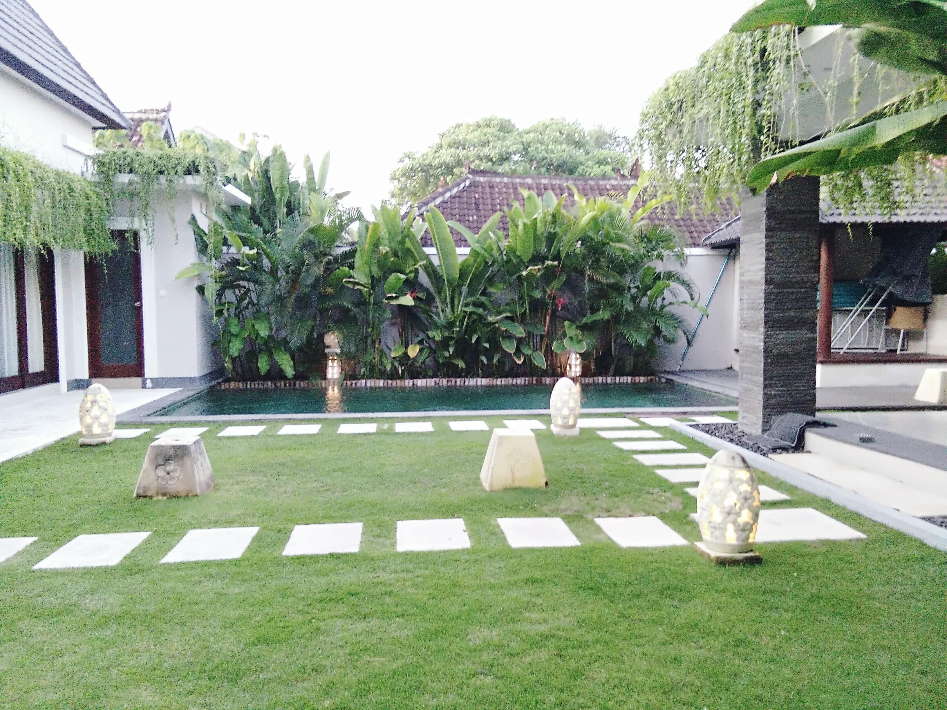 Un patio con piscina, faroles de piedra y abundante vegetación.