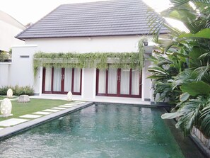 Ein modernes Haus mit Schwimmbad, Garten und gepflegtem Rasen.