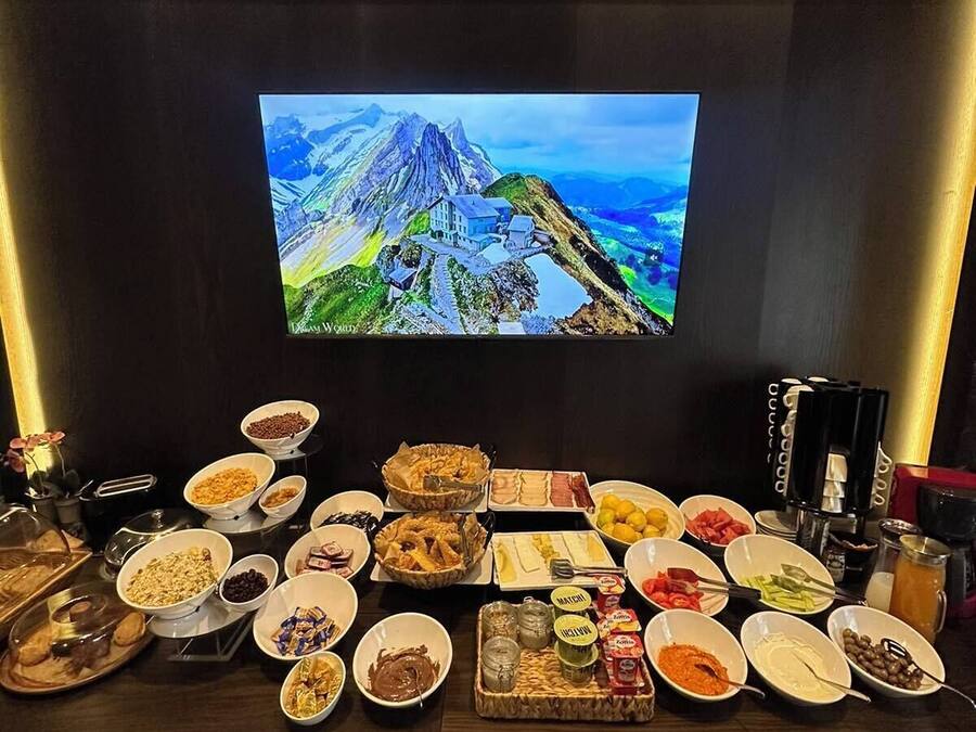 Ett buffébord med olika sorters mat och en tv-skärm som visar ett bergslandskap.