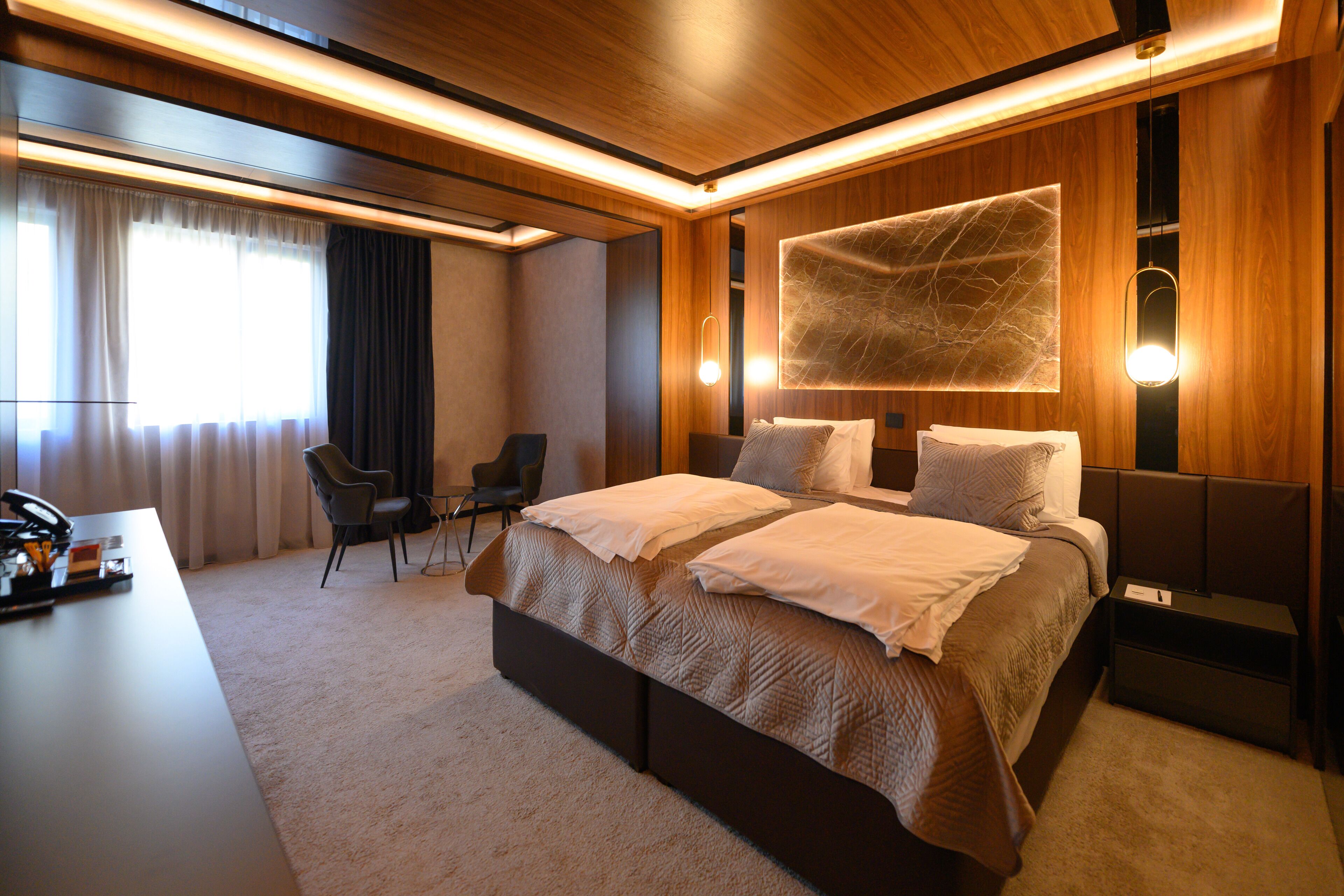 A modern hotel room with a large bed, a desk, and a chair.